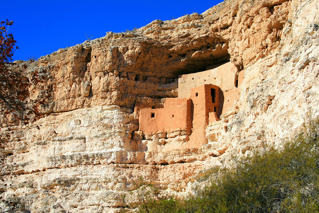 A Native American structure is built into a cliff-face.