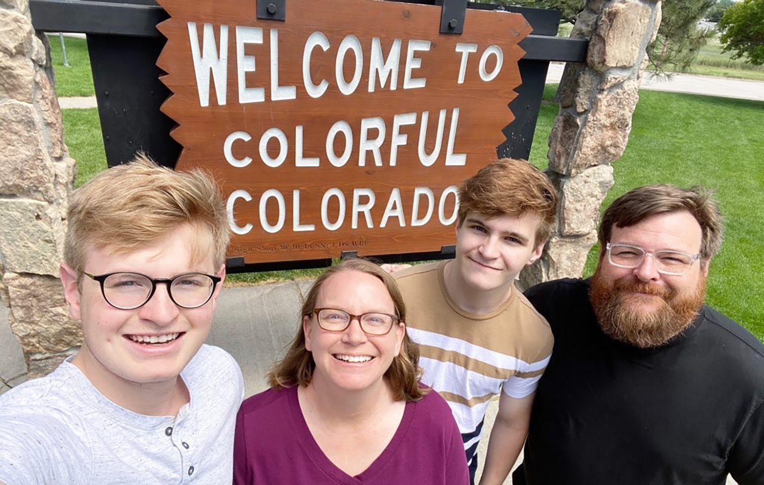 A family of four pose in from fo a sign proclaiming, "Welcome to Colorful Colorado"