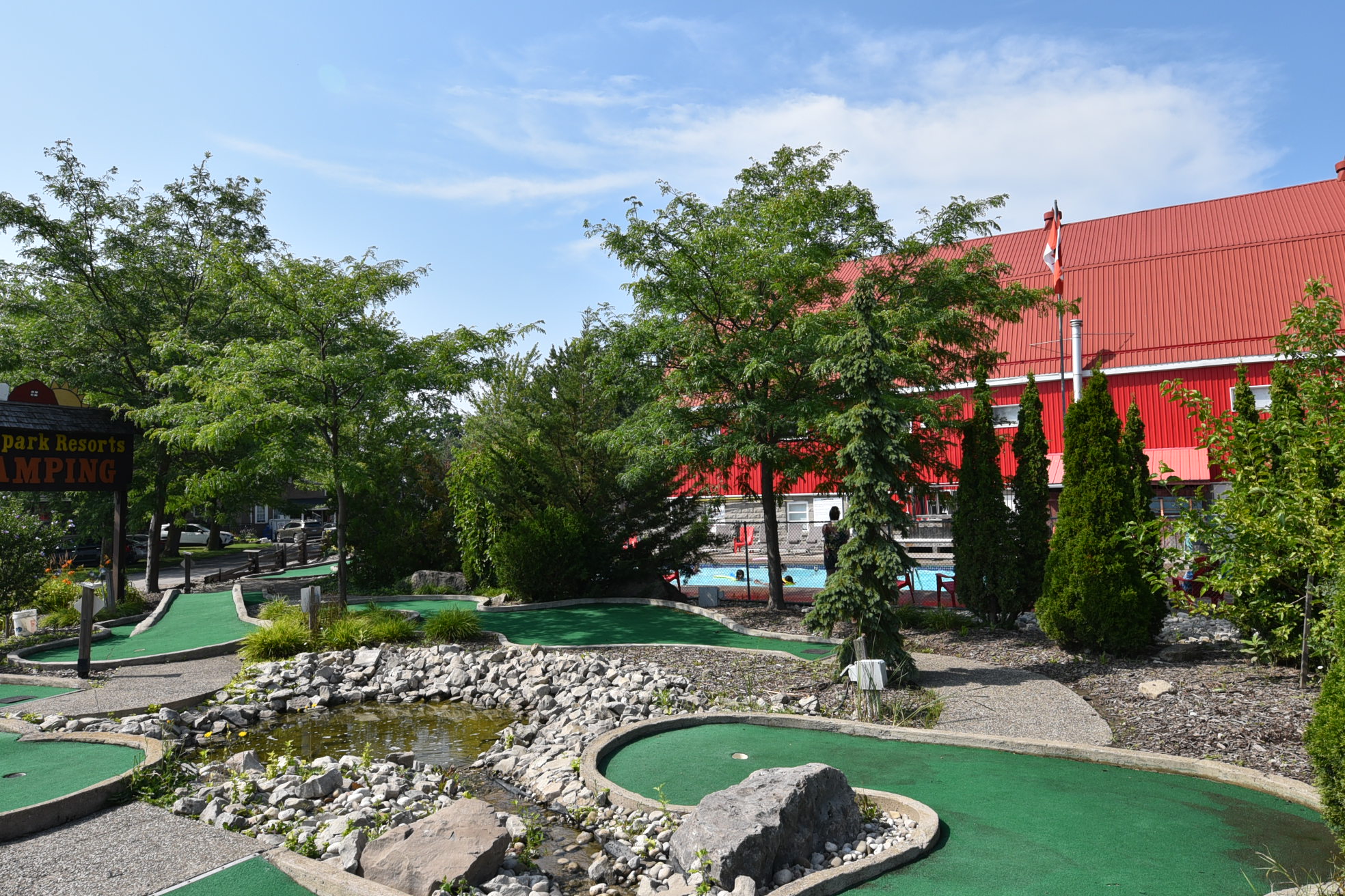 A miniature golf course winds around a lush landscape of trees under blue skies.