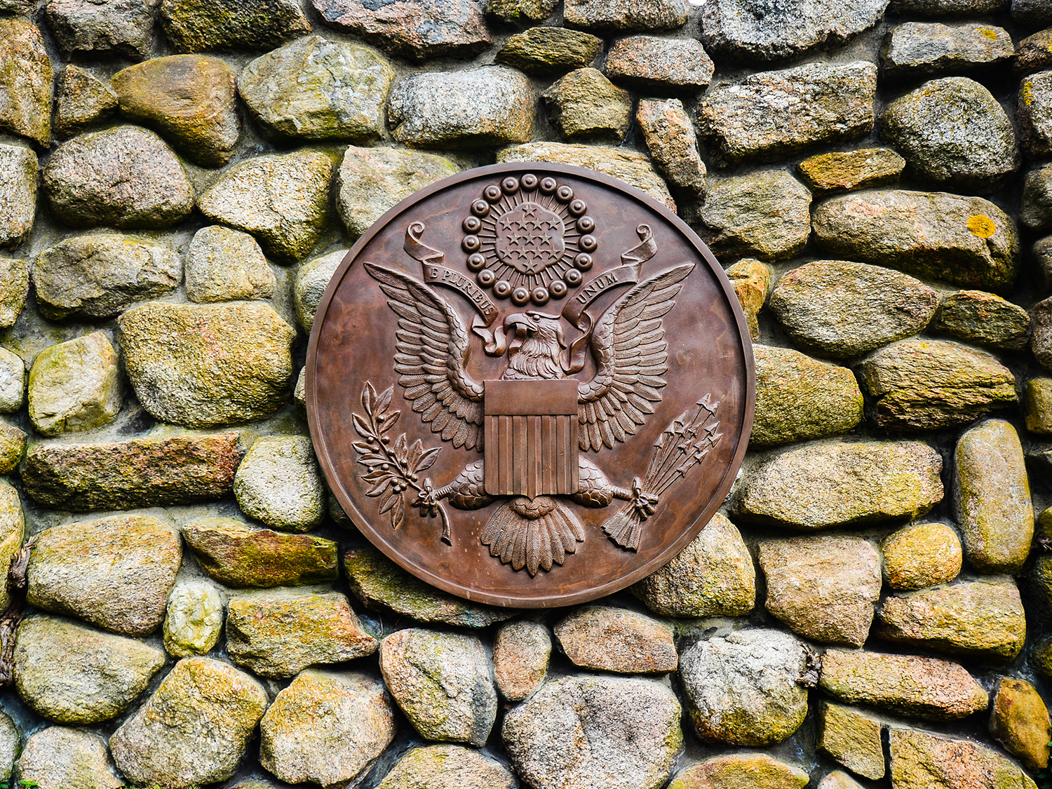 Bronze presidential seal mounted on a wall made of stones.