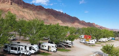 RVs parked on a row of spaces at the foot of a rugged desert slope.