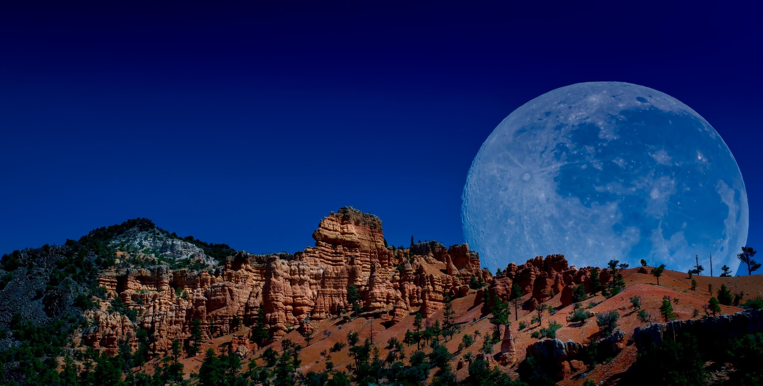 Bryce Valley Ranch — Moon rising over a rocky ridge.