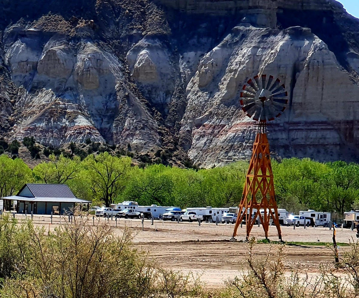 RV park against a bluff with windmill in the foreground.
