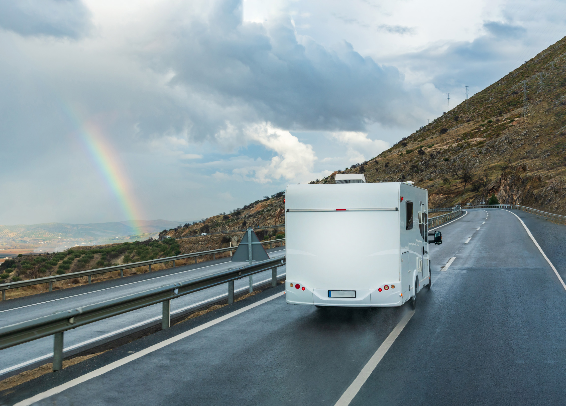 An RV driving toward a rainbow.