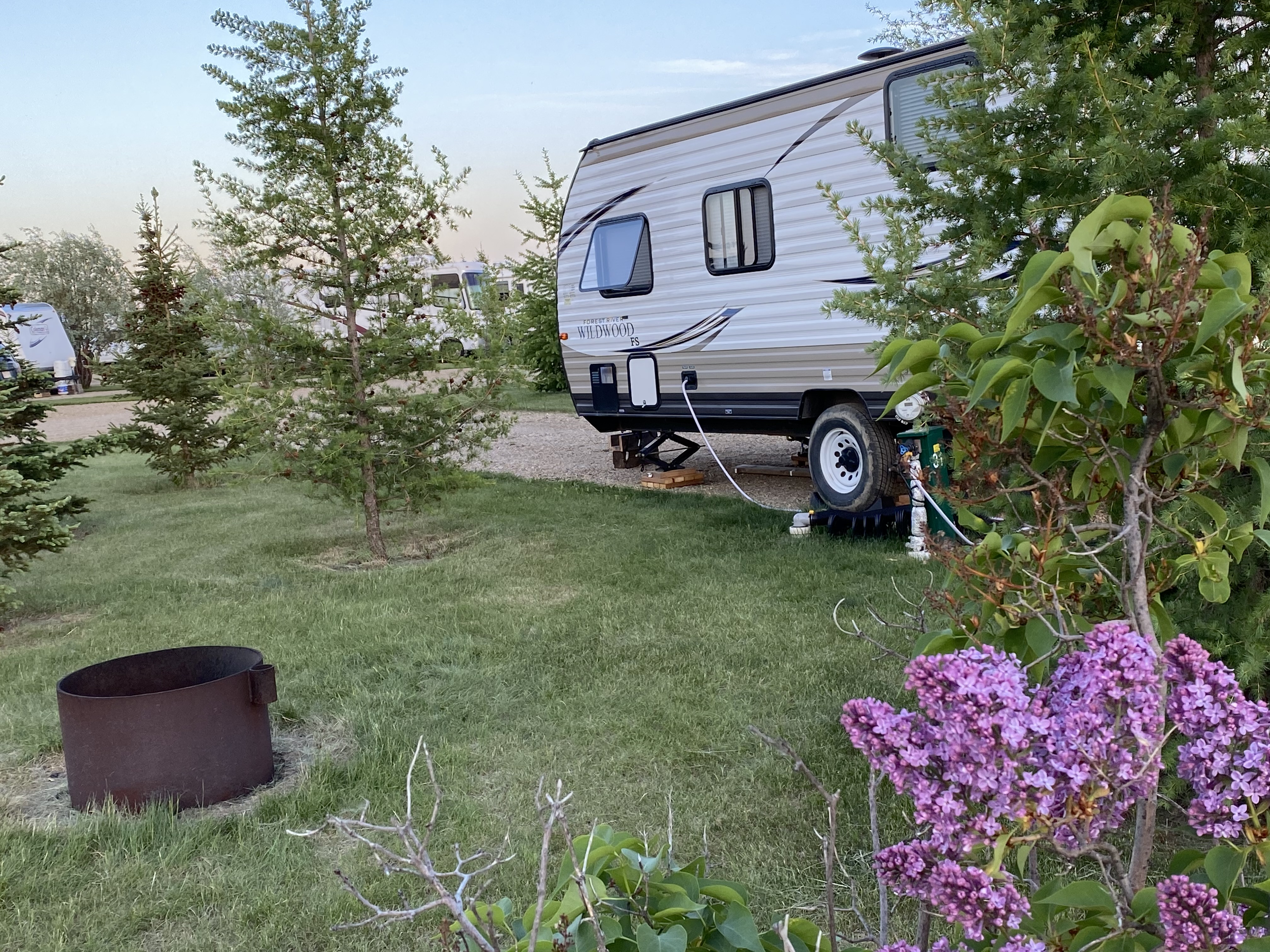 A travel trailer parked on a pad surrounded by trees and grass.