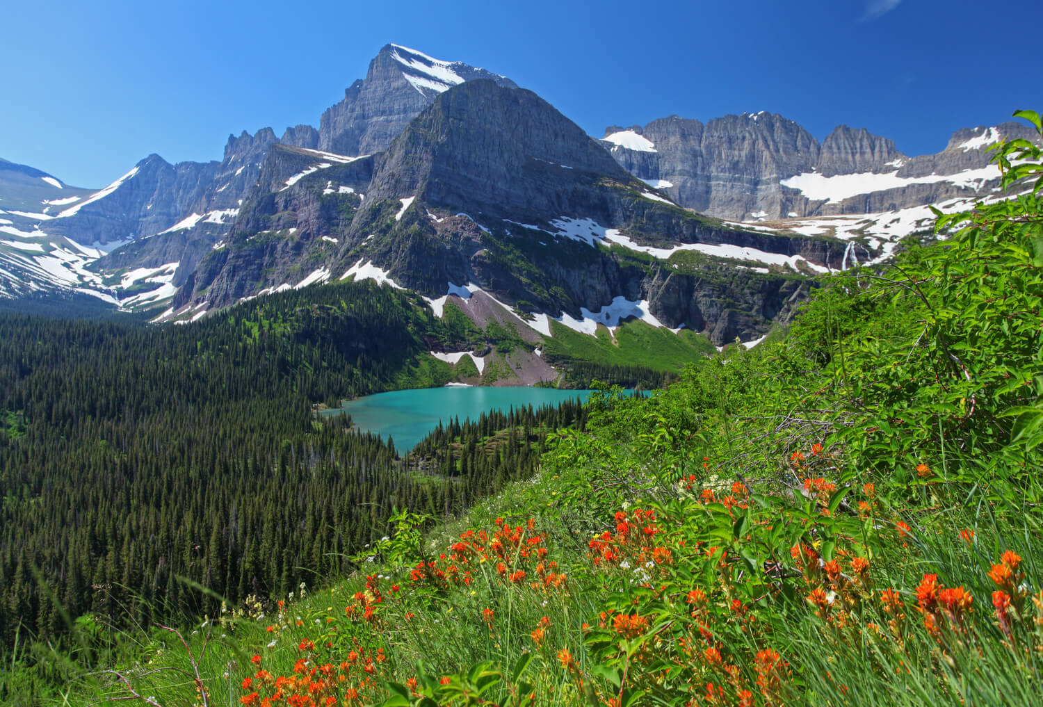 An emerald lake with craggy mountain in background.