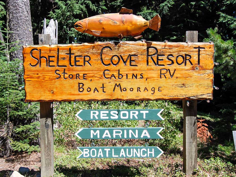 A wooden with the carved words, Shelter Cove Resort, with arrows pointing to marina, resort and boat launch.