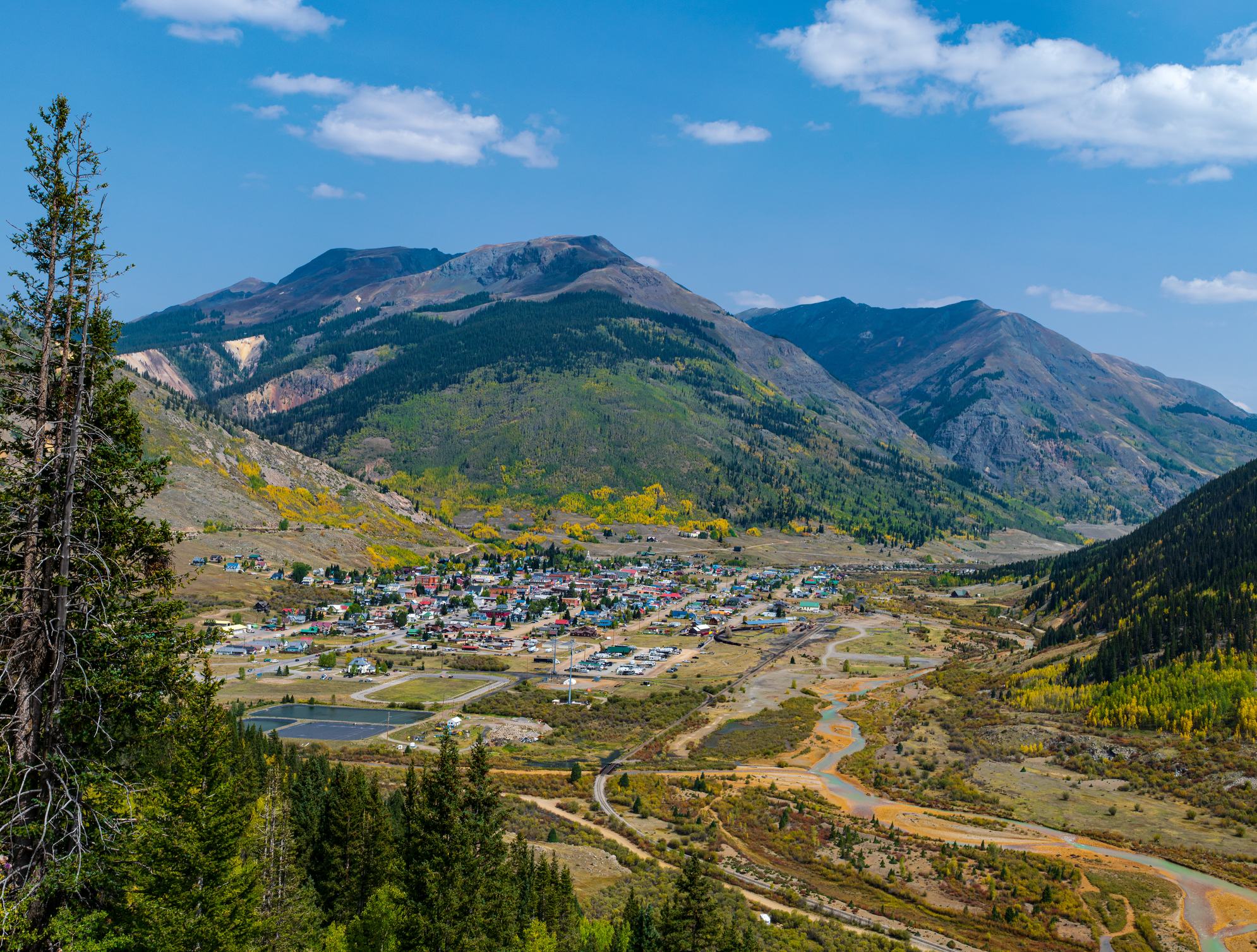 View of small town from high elevation amid high mountain peaks.