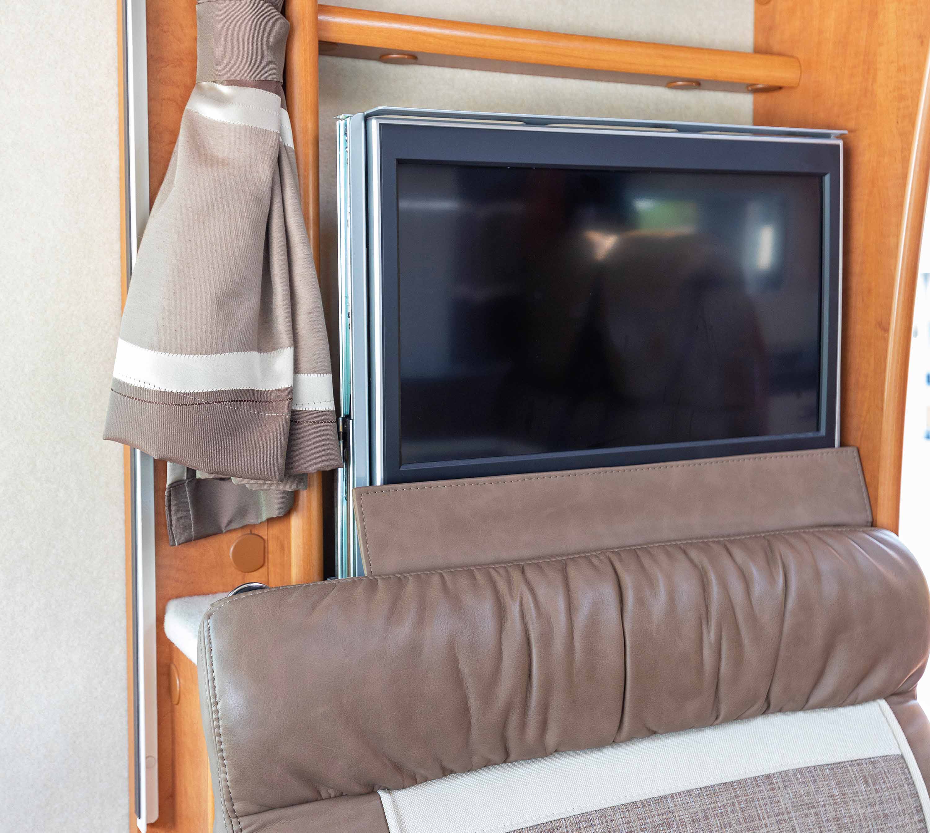A TV rises out of its hidden position behind a dinette via a televator in an RV.