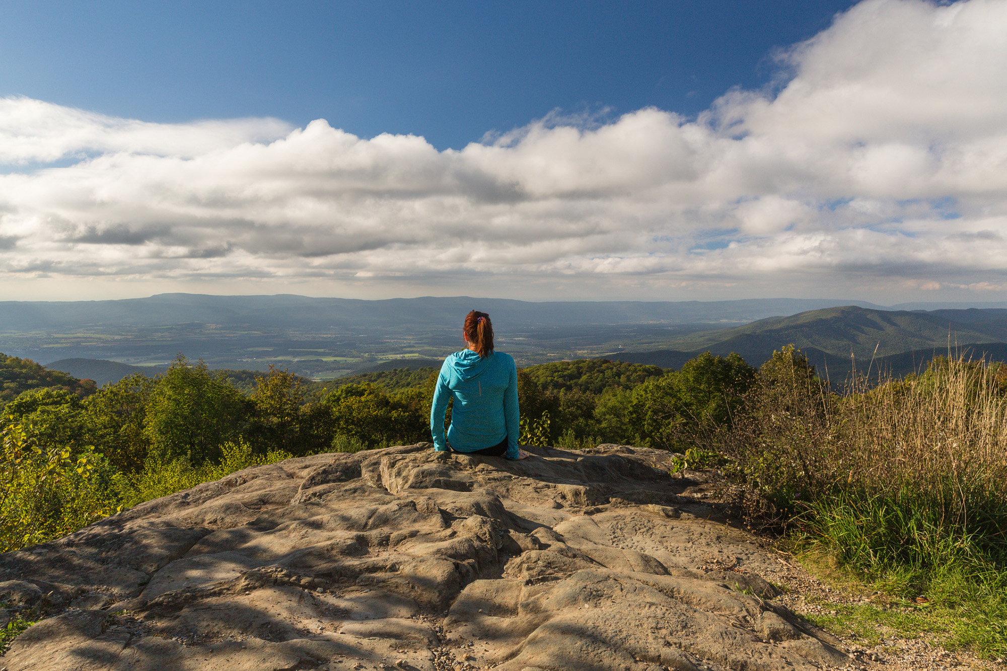 Woman sits on a cliff overlooking natural splendor
