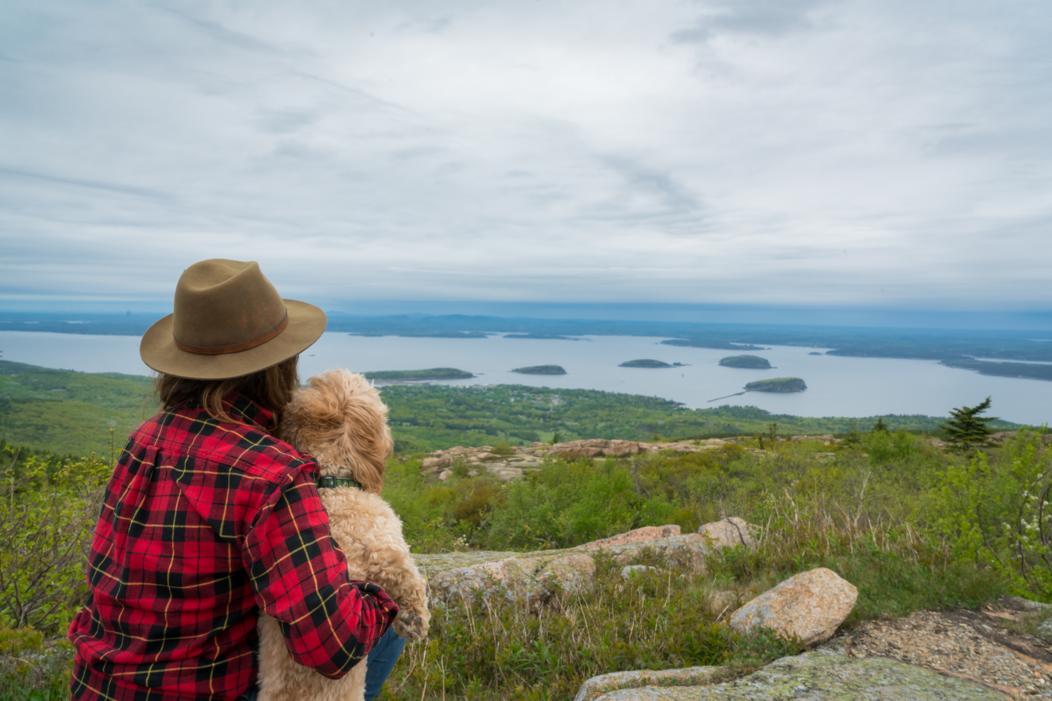Woman and Dog enjoy beautiful view from atop a mountain.