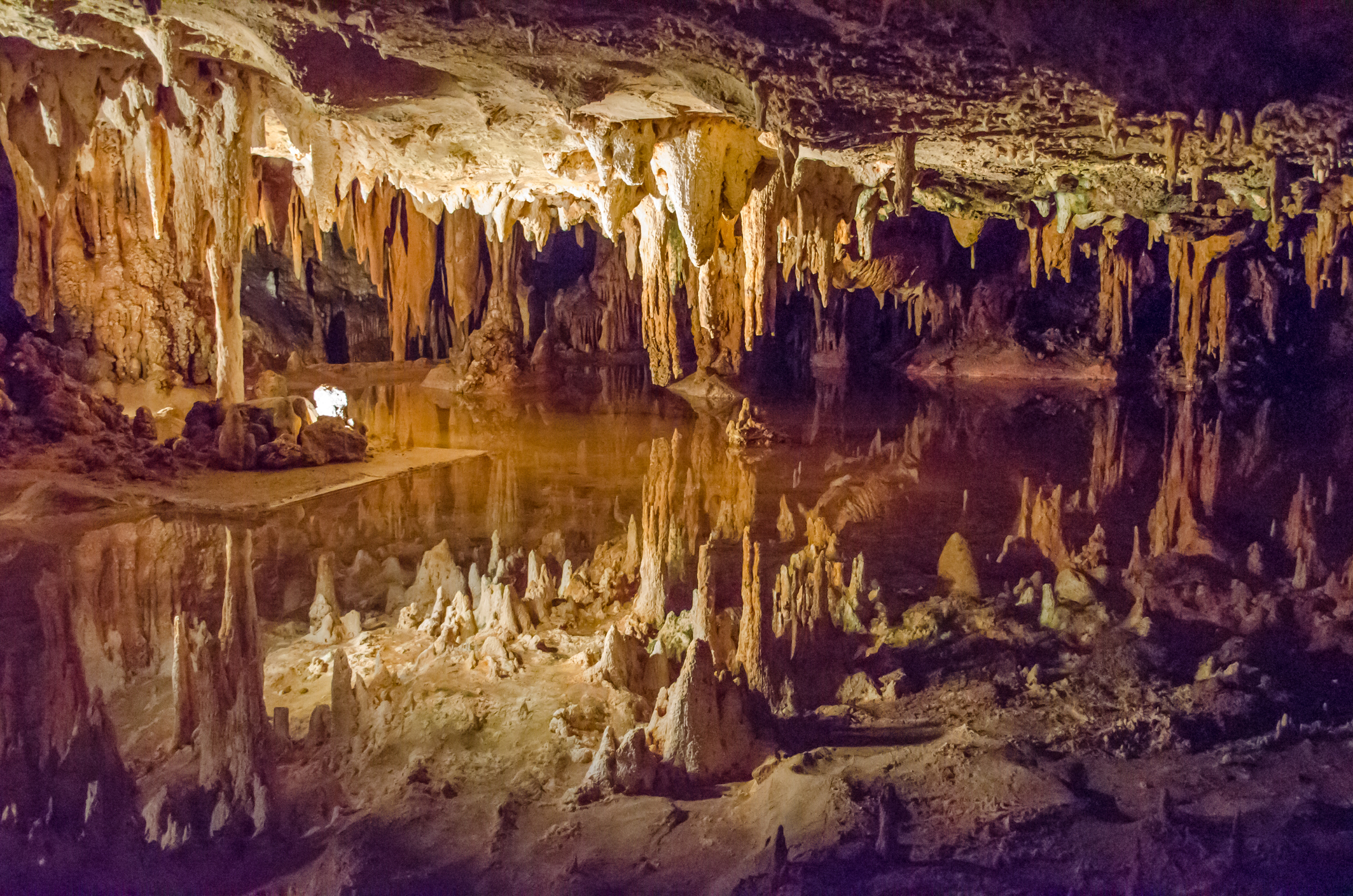 Stalactites reflected on water in an underground cavern.