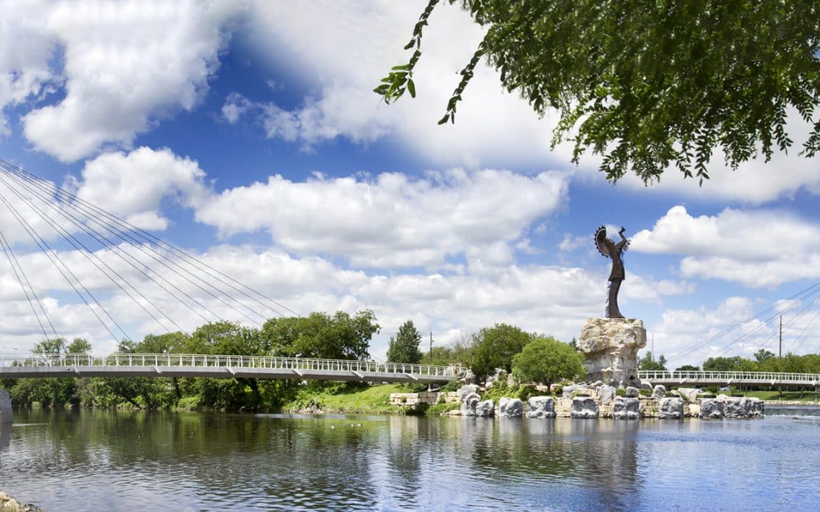 a statue of a Native American overlooking a river.