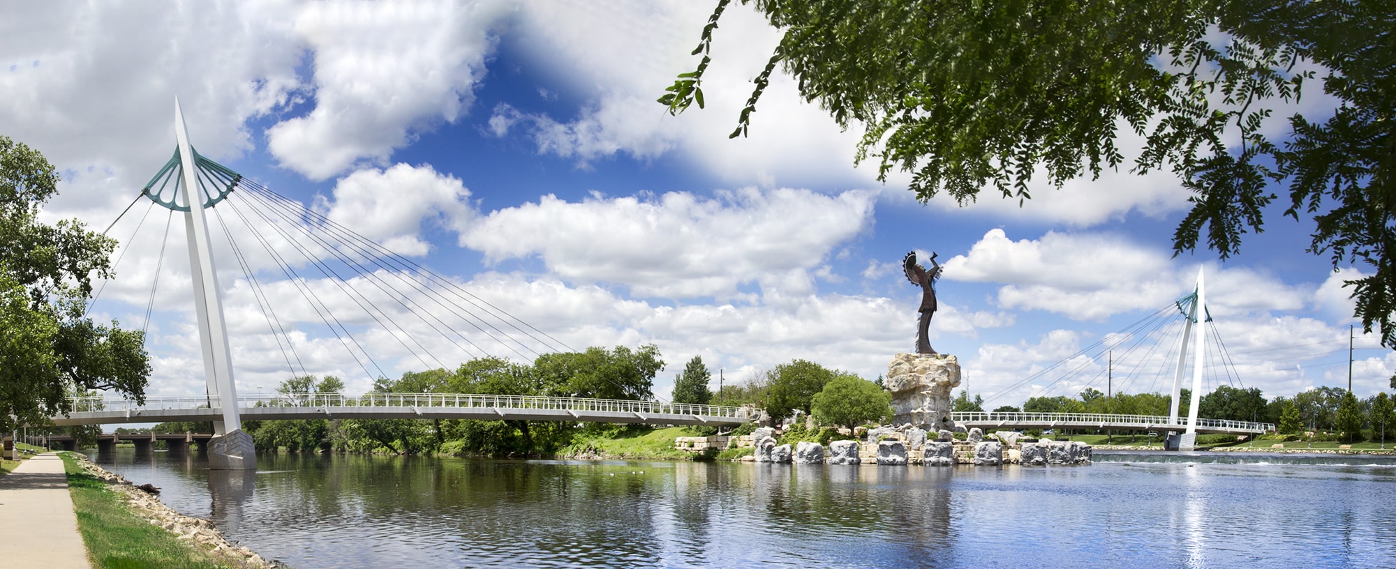 a statue of a Native American overlooking a river.