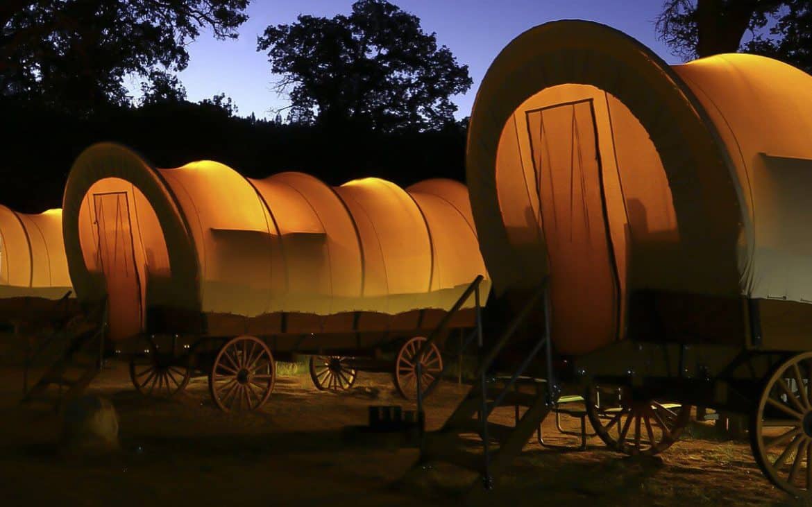 A row of conestoga wagons illuminated from within