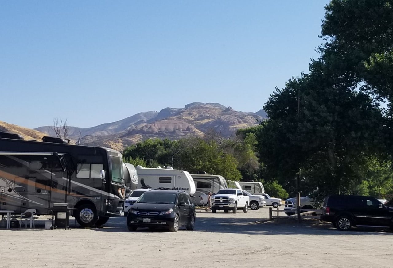 RVs in a park with mountains looming in the background.