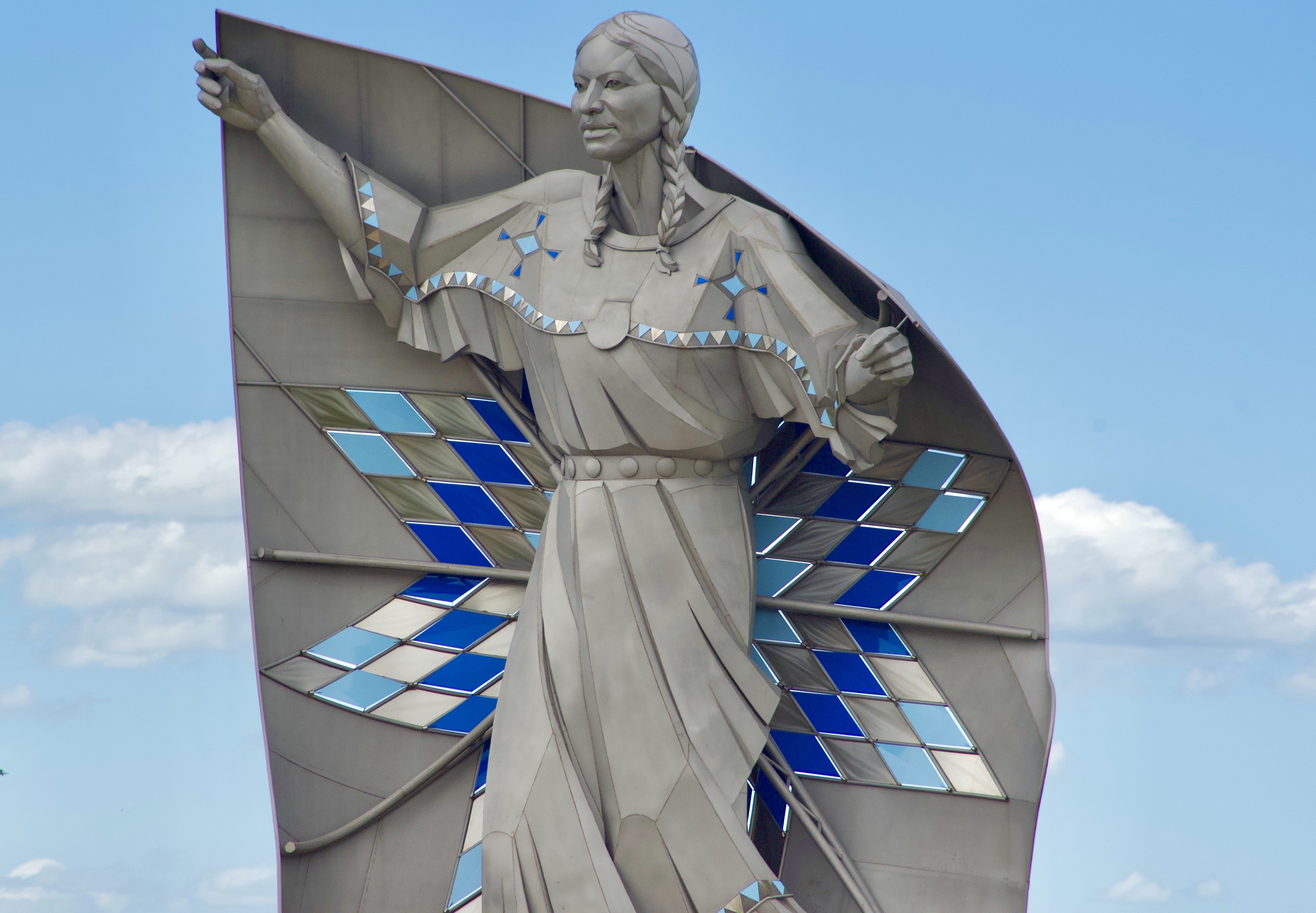 Statue of a Native American woman with a colorful quilt.