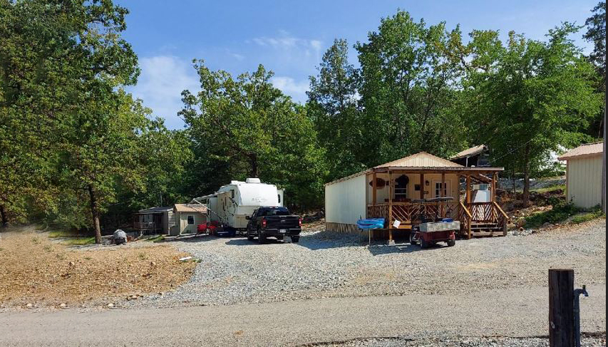 RV and cabin amid high trees.