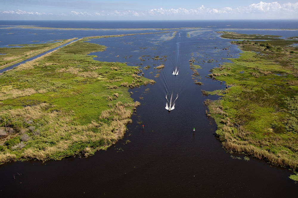 Aerial shot of boats entering a lake through a channel.