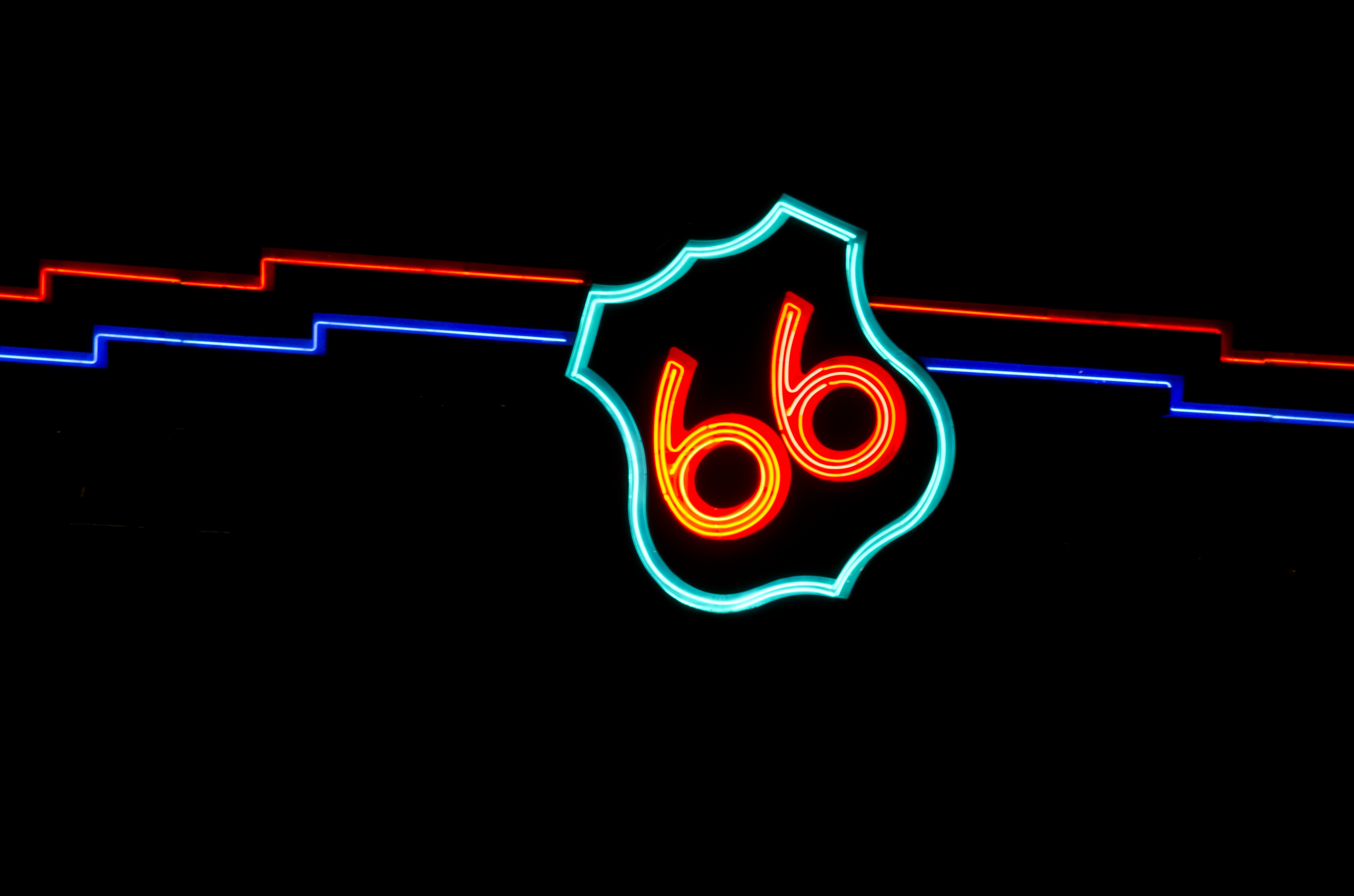 An overpass sign made of neon in the shape of a highway sign with the numbers, 66.