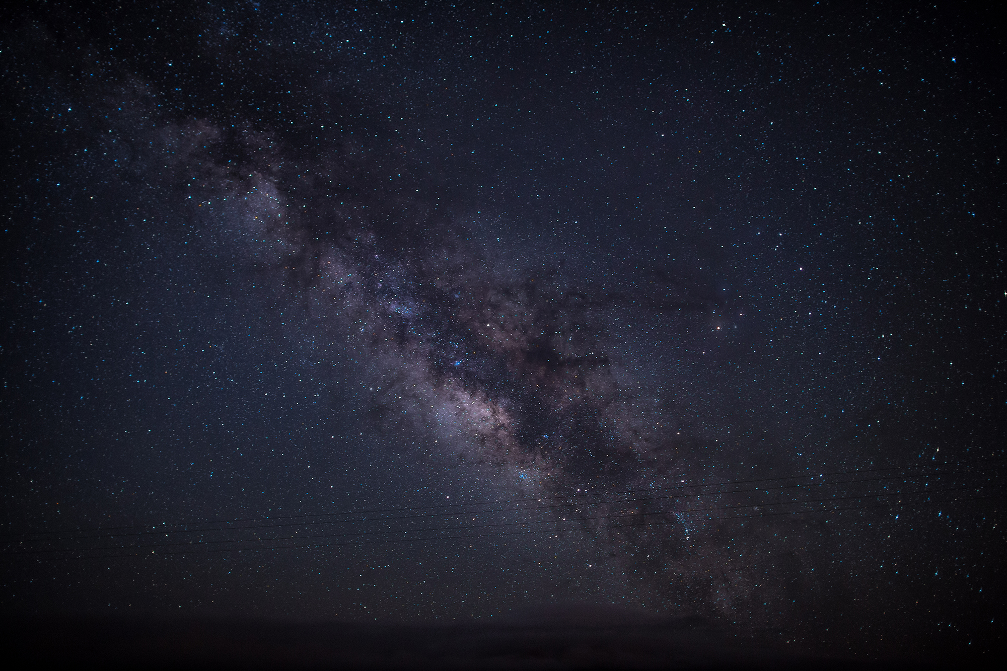 A thick band of stars dramatically crosses the sky at a diagonal angle.