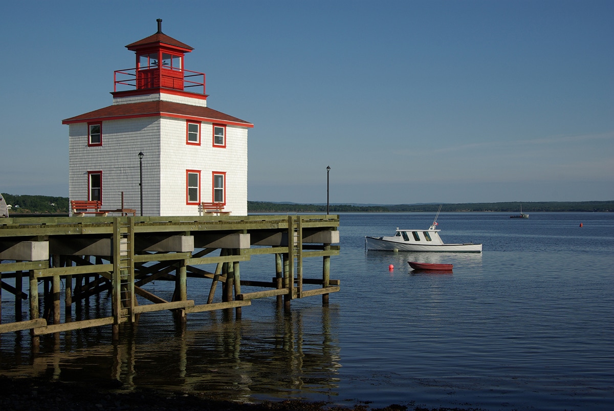A lighthouse built on a dock overlooking a placid bay.