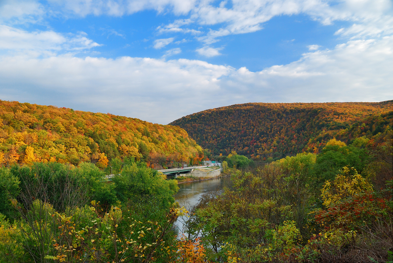 An interstate huges the edge of an autumn gilded hill.