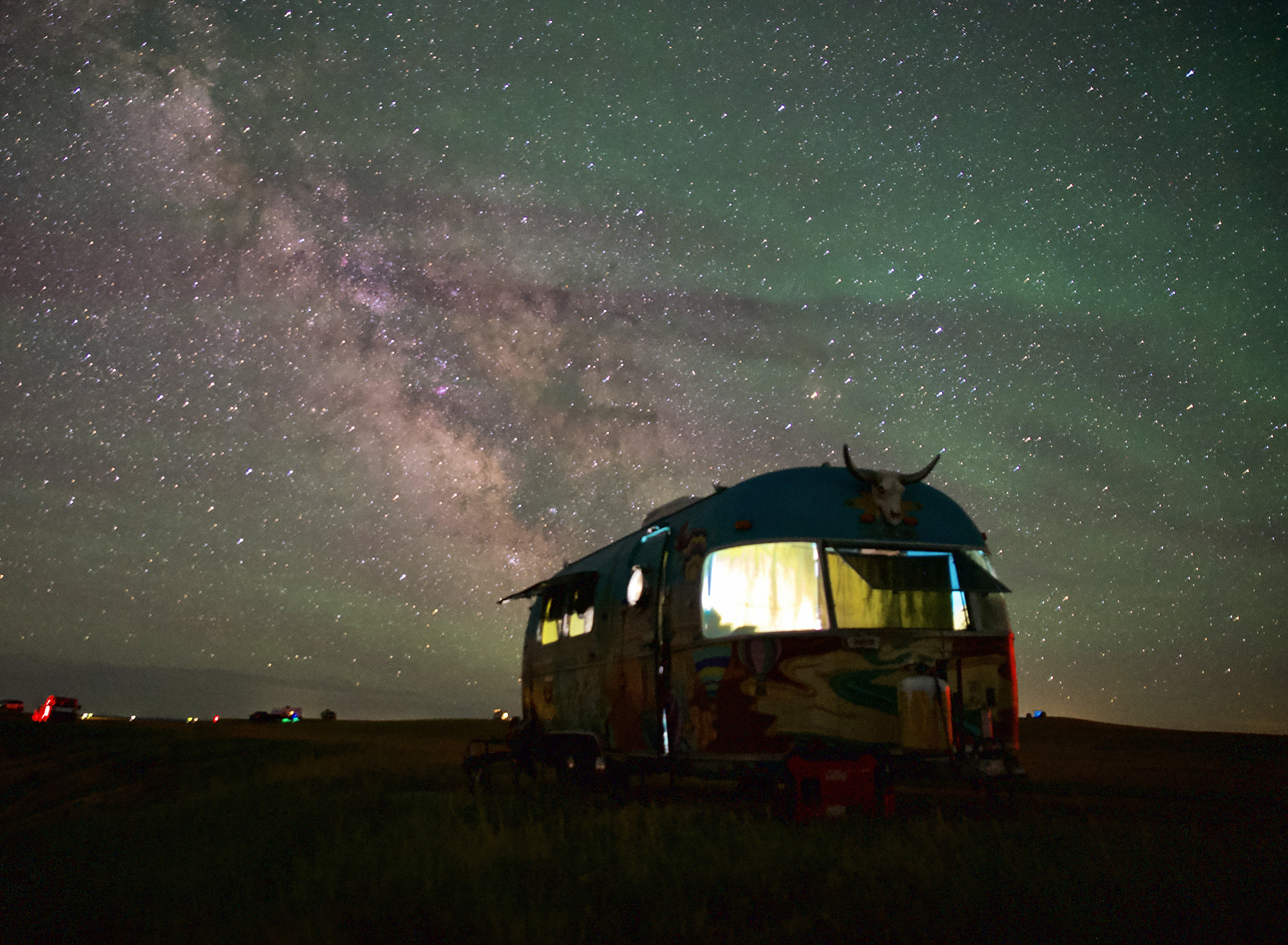 An airstream trailer under a thick canopy of stars. 