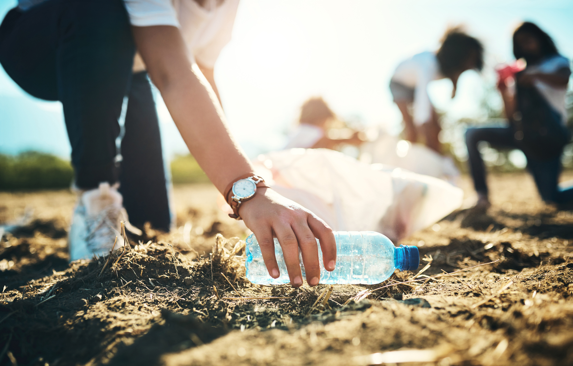 Cleaning up a plastic bottle in a field.