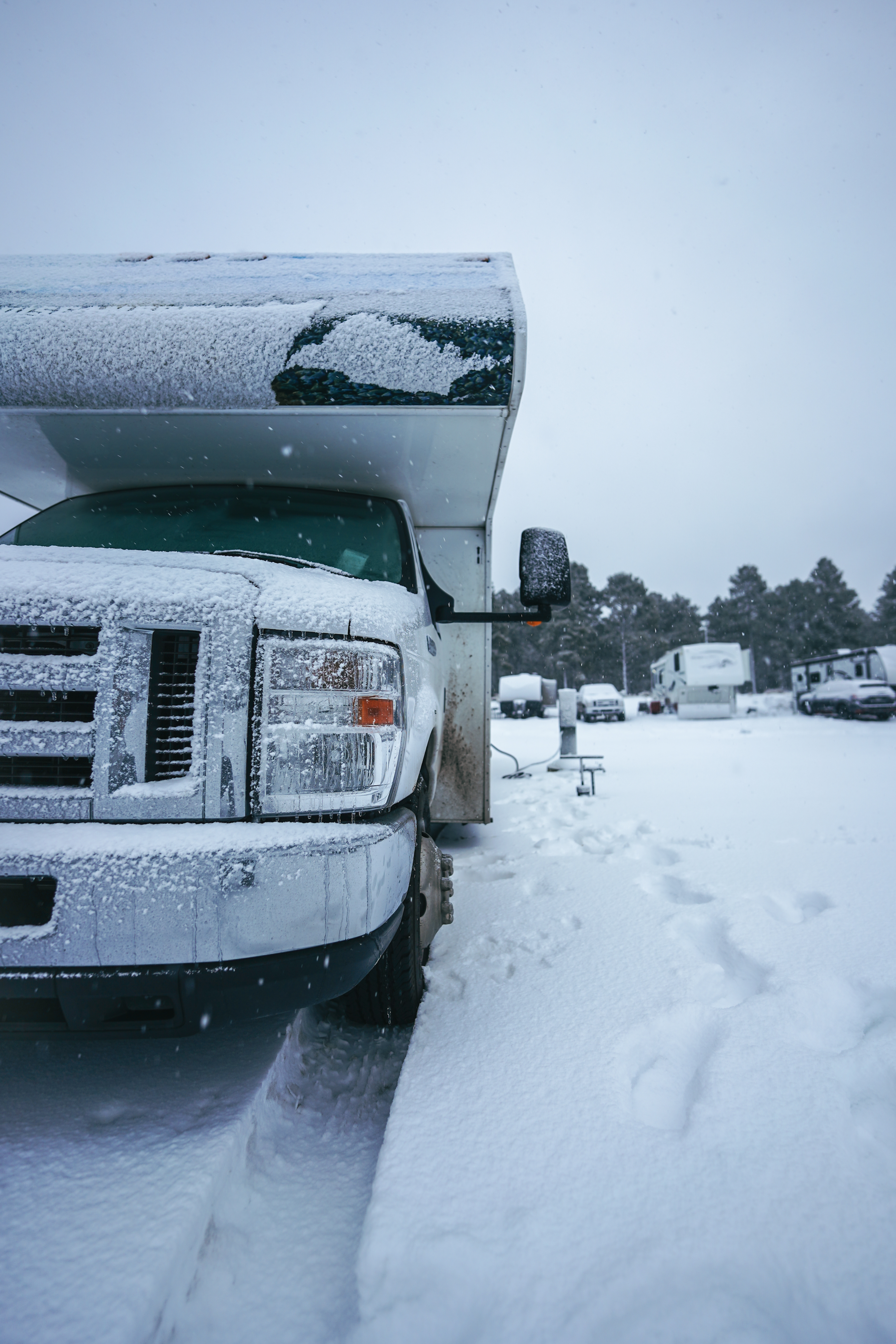 A truck camper parked in an area with foot-thick snow.