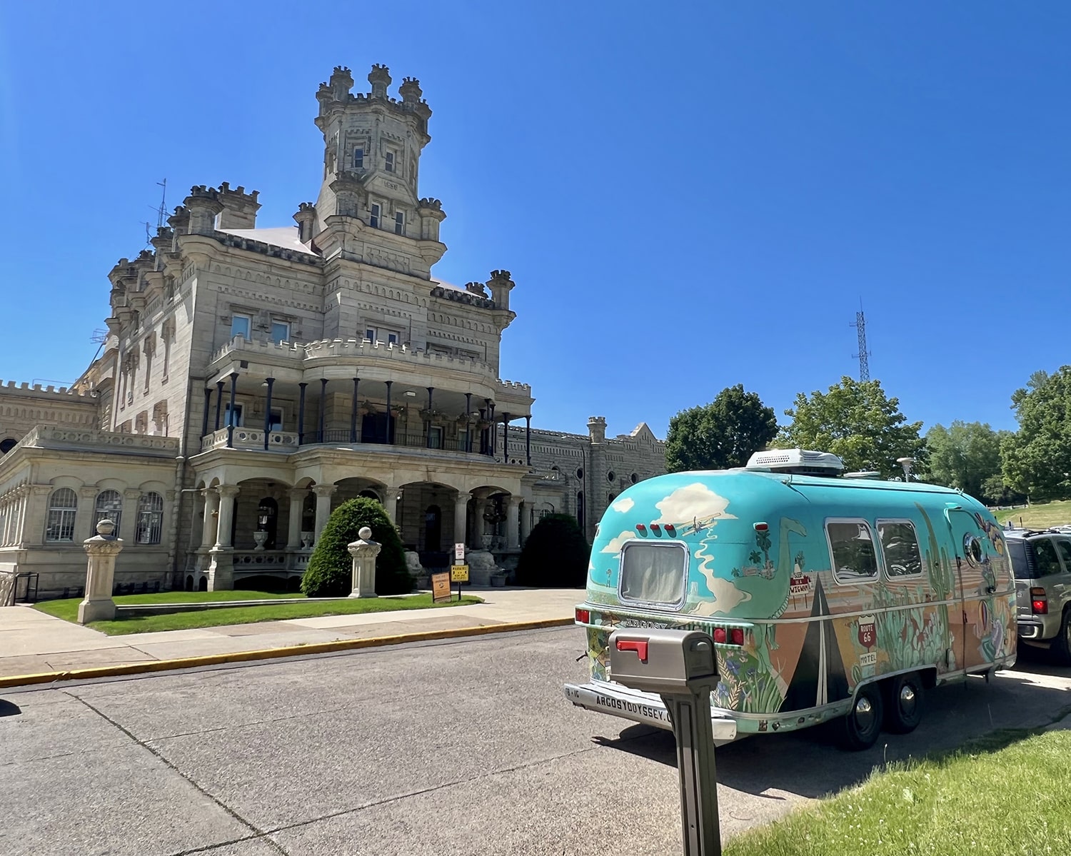 Colorful Airstream trailer parked in front of gothic building.
