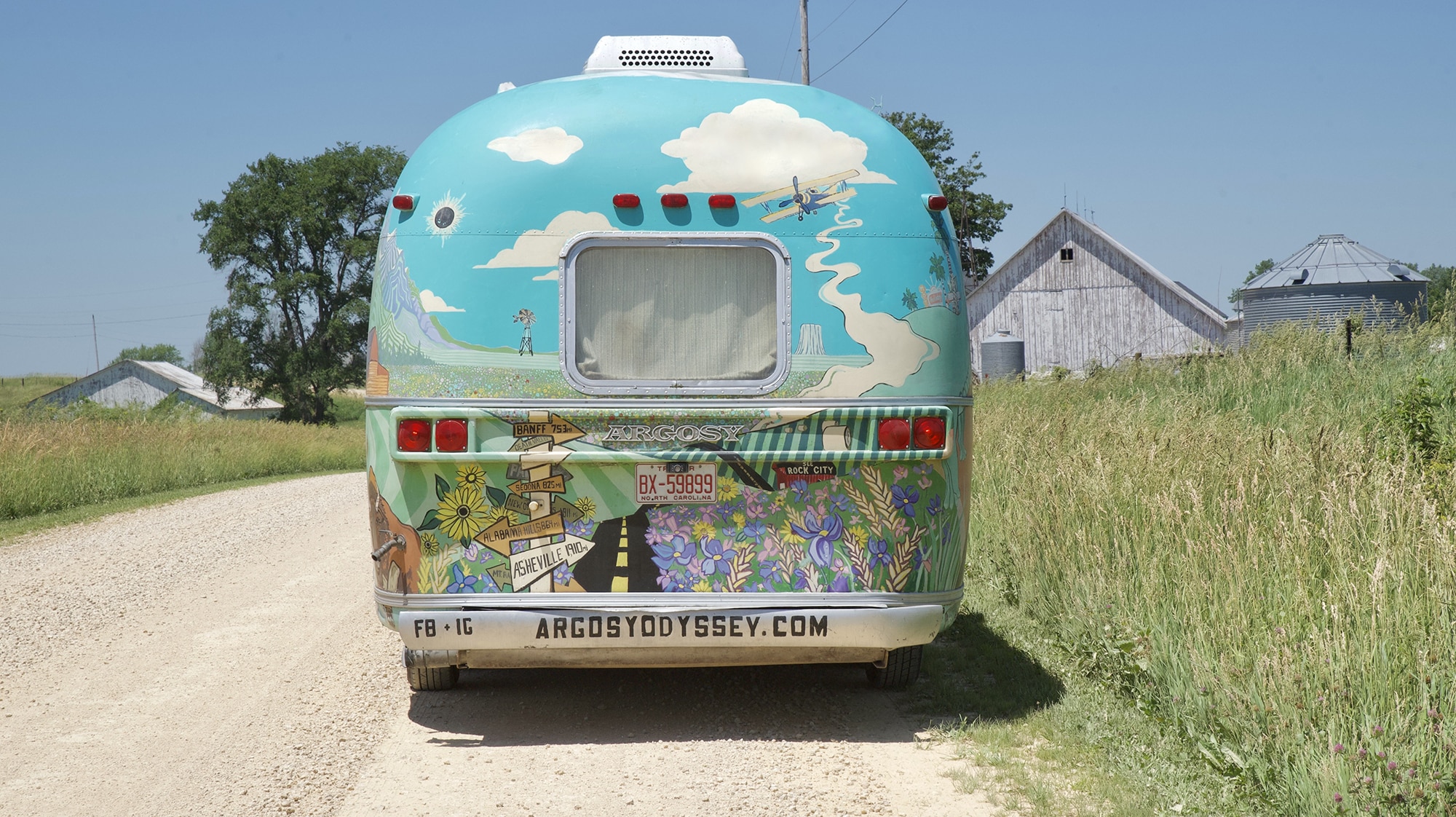 Colorful Airstream trailer parked on side of dirt road.