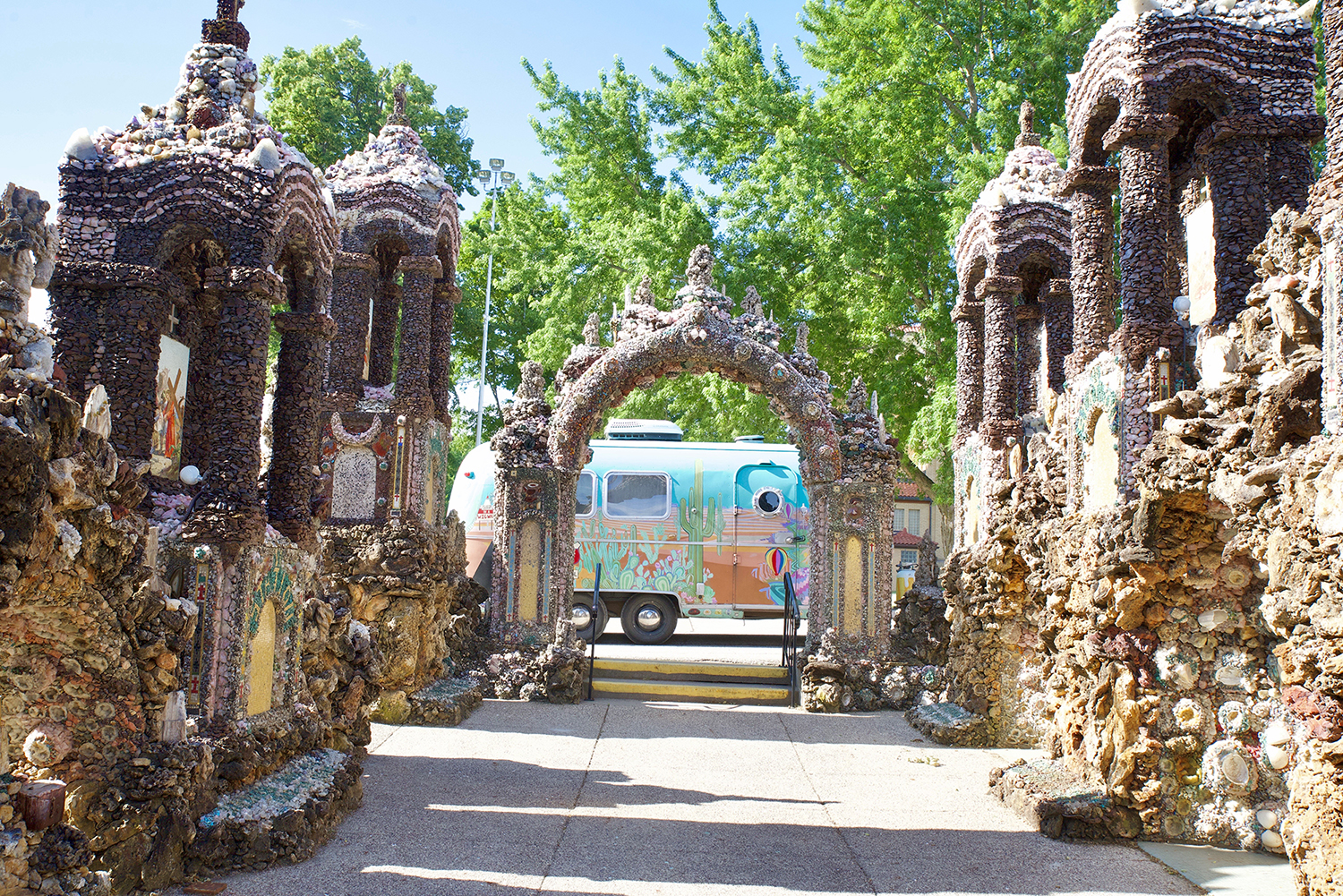 Colorful Airstream trailer as viewed through a grotto arch from within grotto.