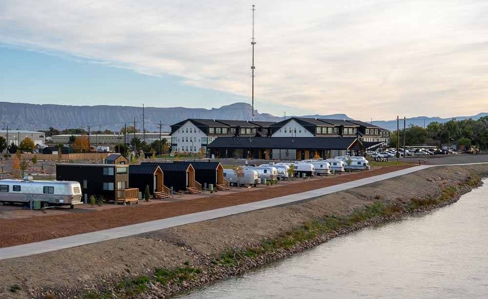 Airstreams lined up on the bank of a river.