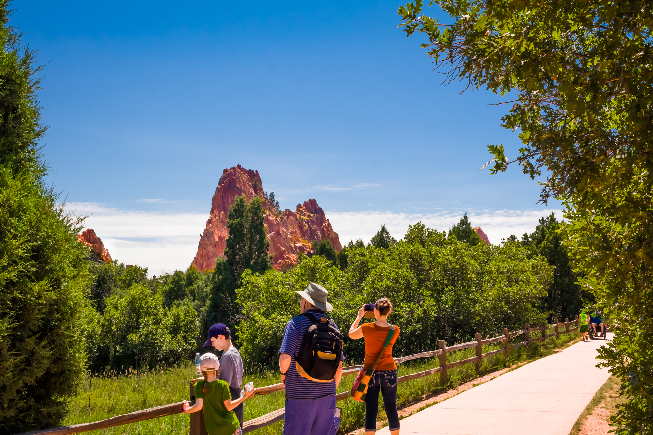 A family observes a tall rocky mountain on horizon.