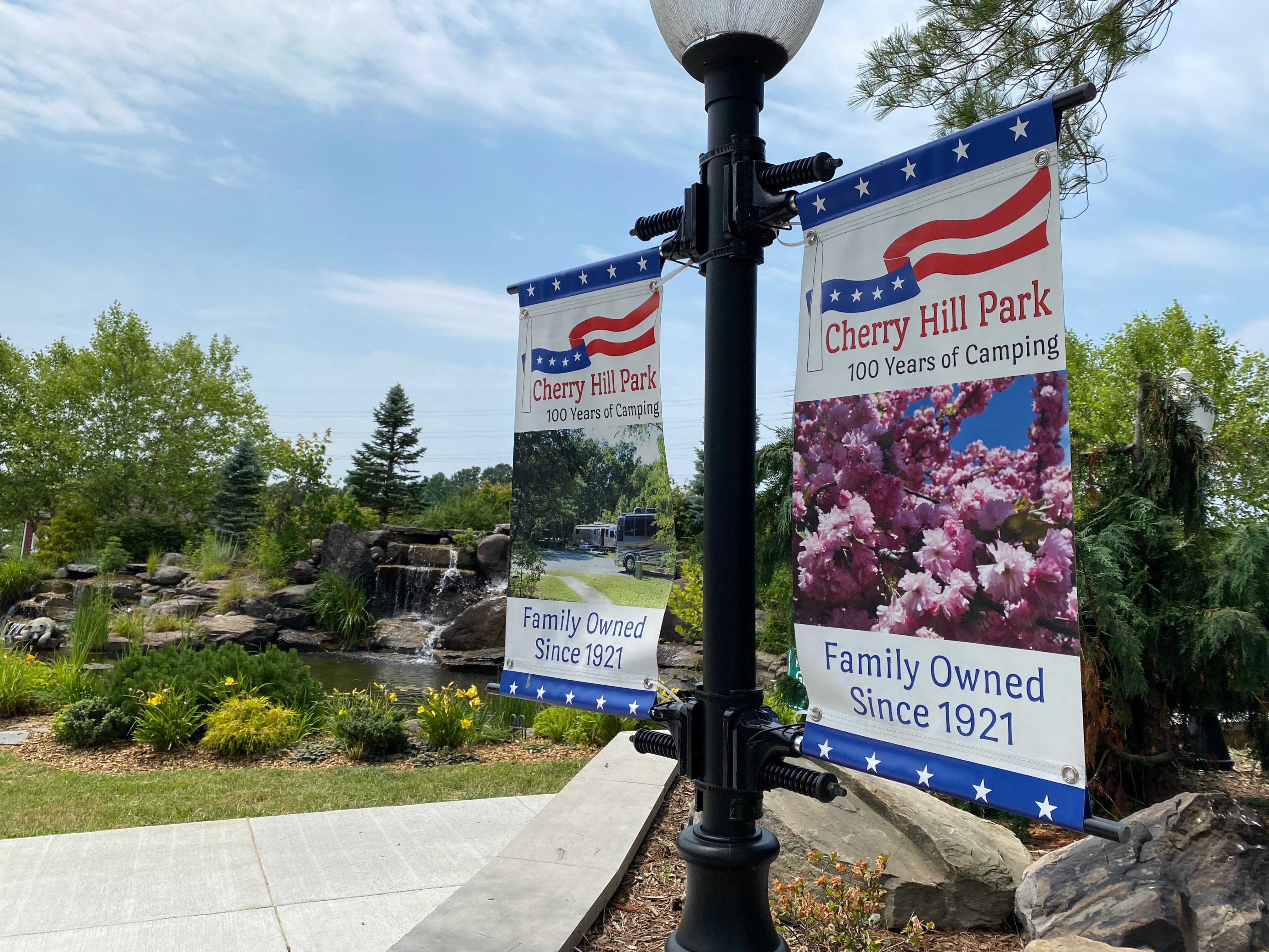 Lampposts with signs indicating Cherry Hill Park attached with nice landscaping in background.