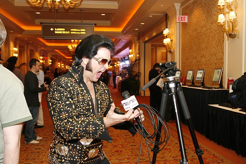 An Elvis impersonator emotes into a microphone.