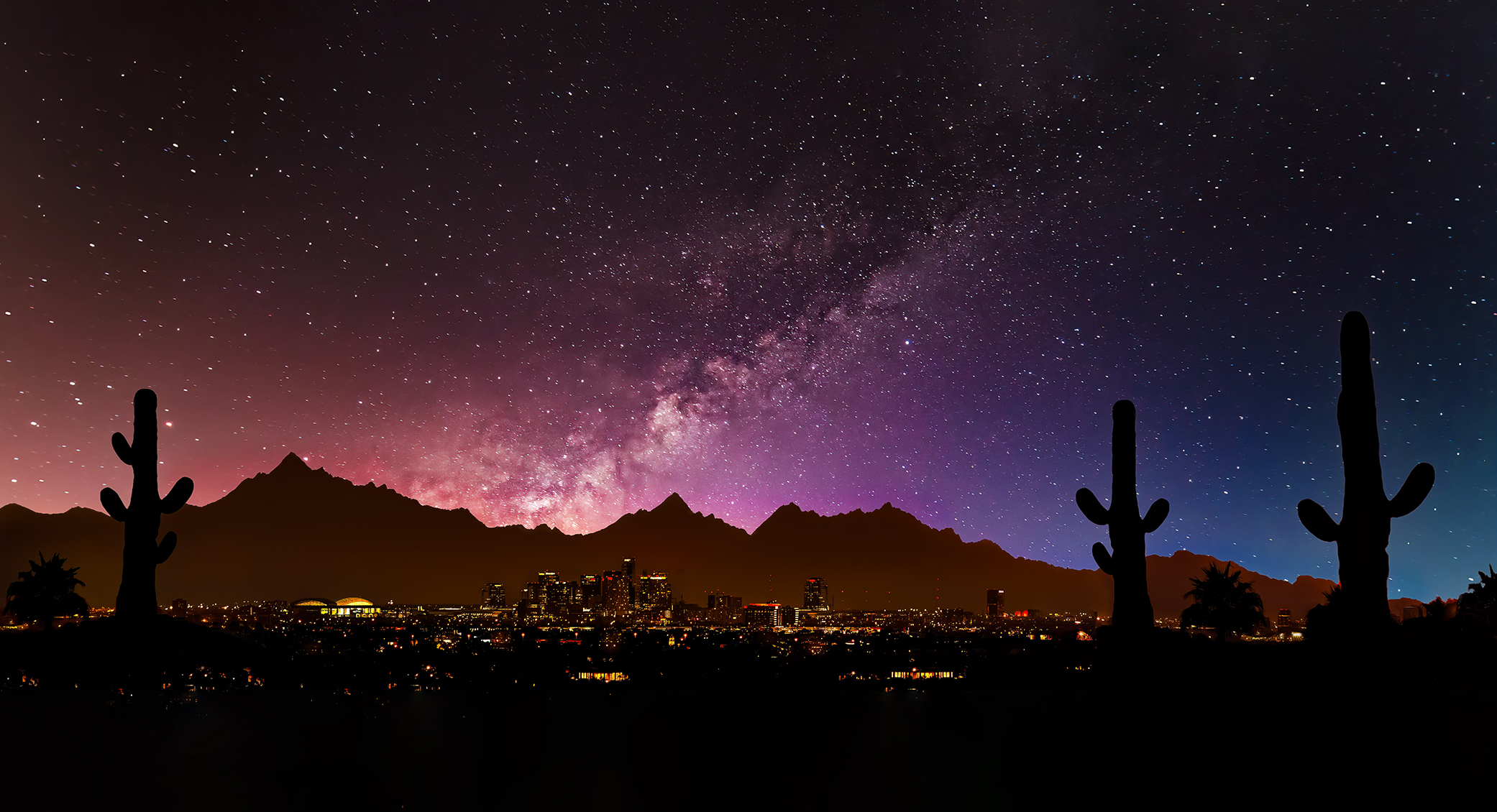 Starry sky over cityscape with cacti silhouettes in foreground.