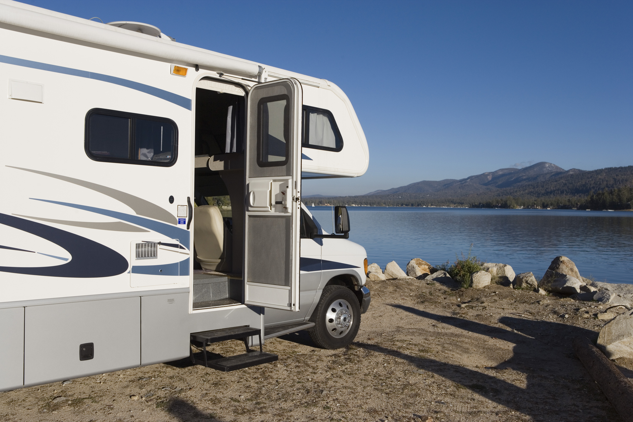 Beginner RV owners — RV camped on the shore of a scenic lake.