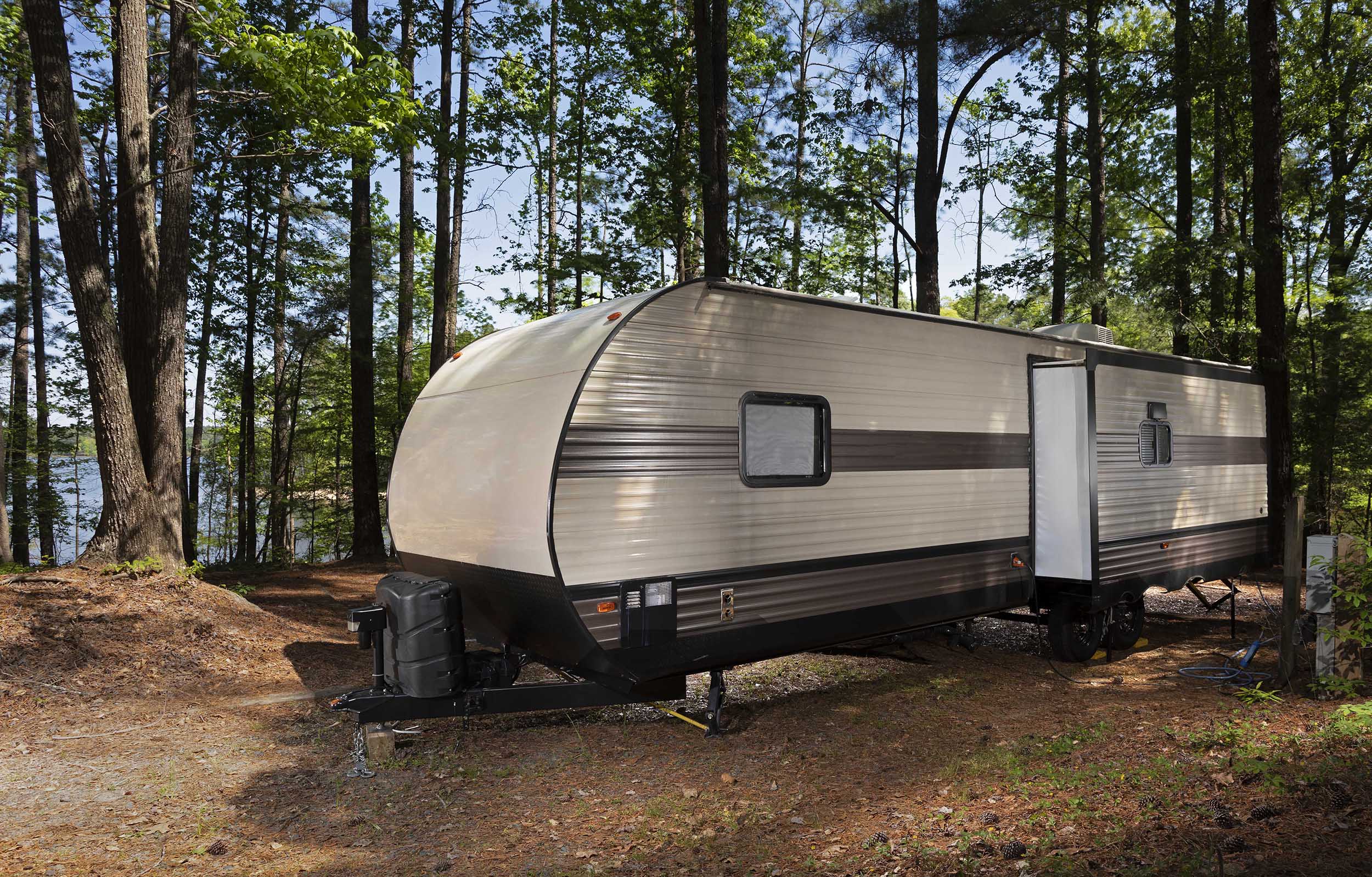 A travel trailer parked in a wooded campsite