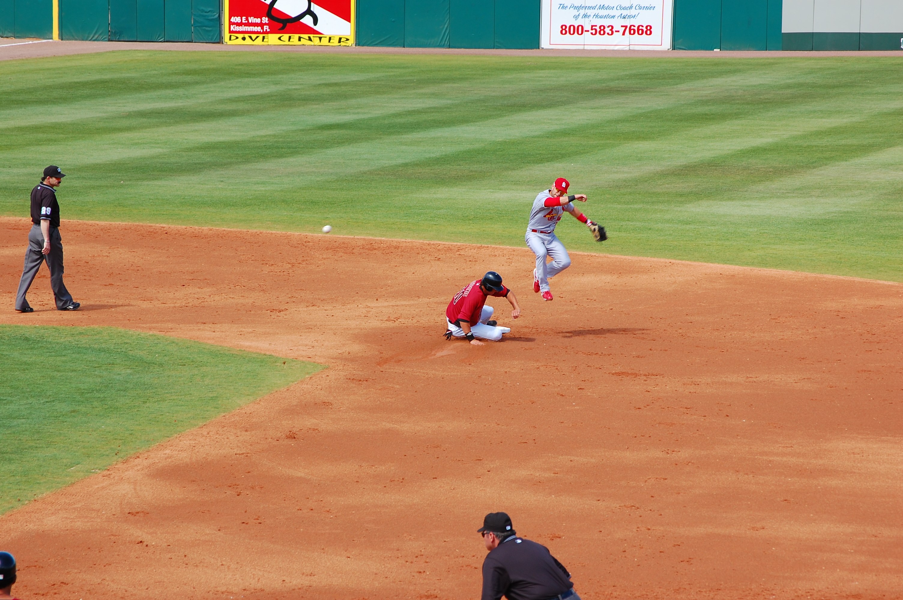 A baseball runner slides into second base. 