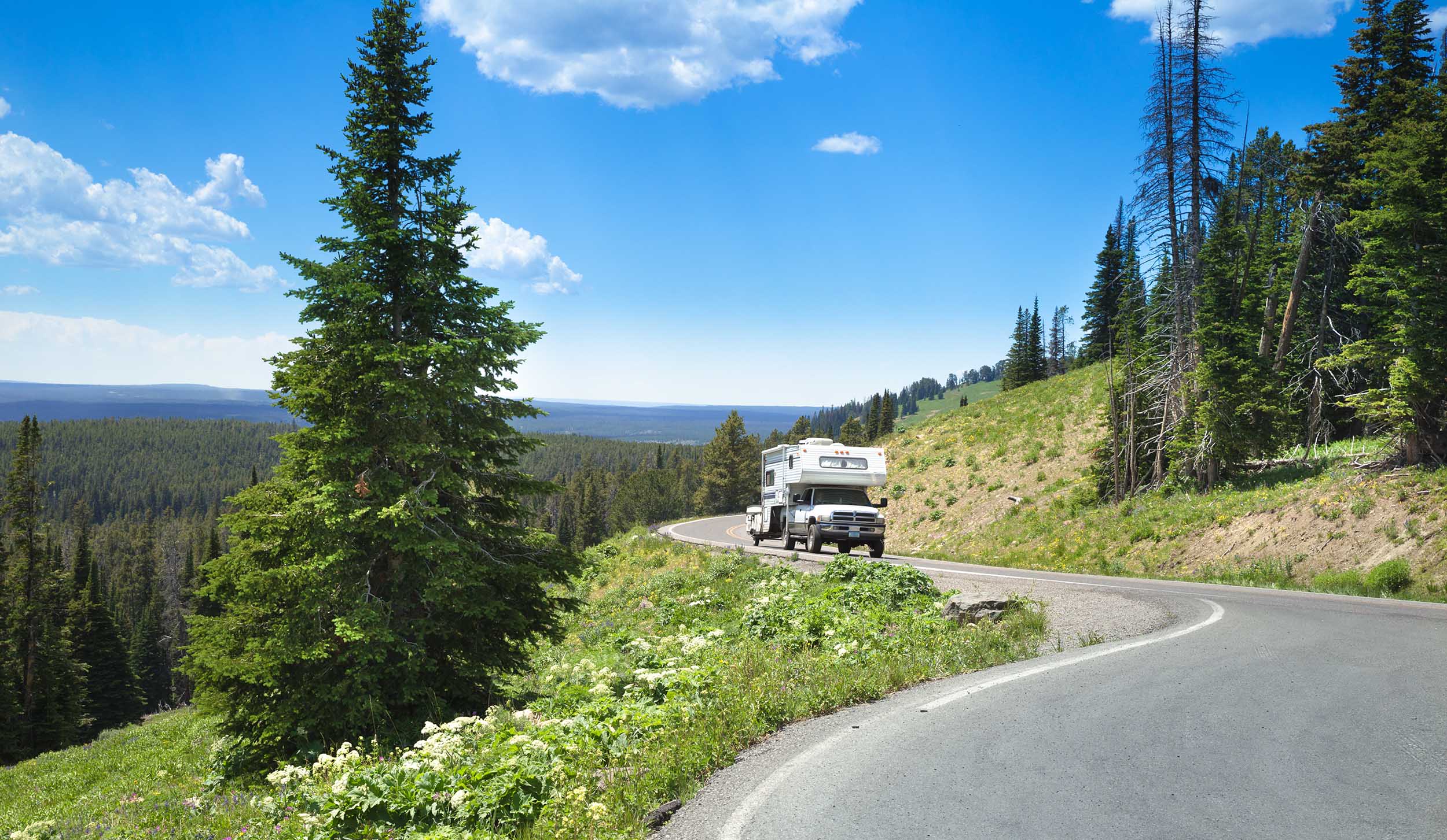 Truck camper navigating the curve of a mountain highway