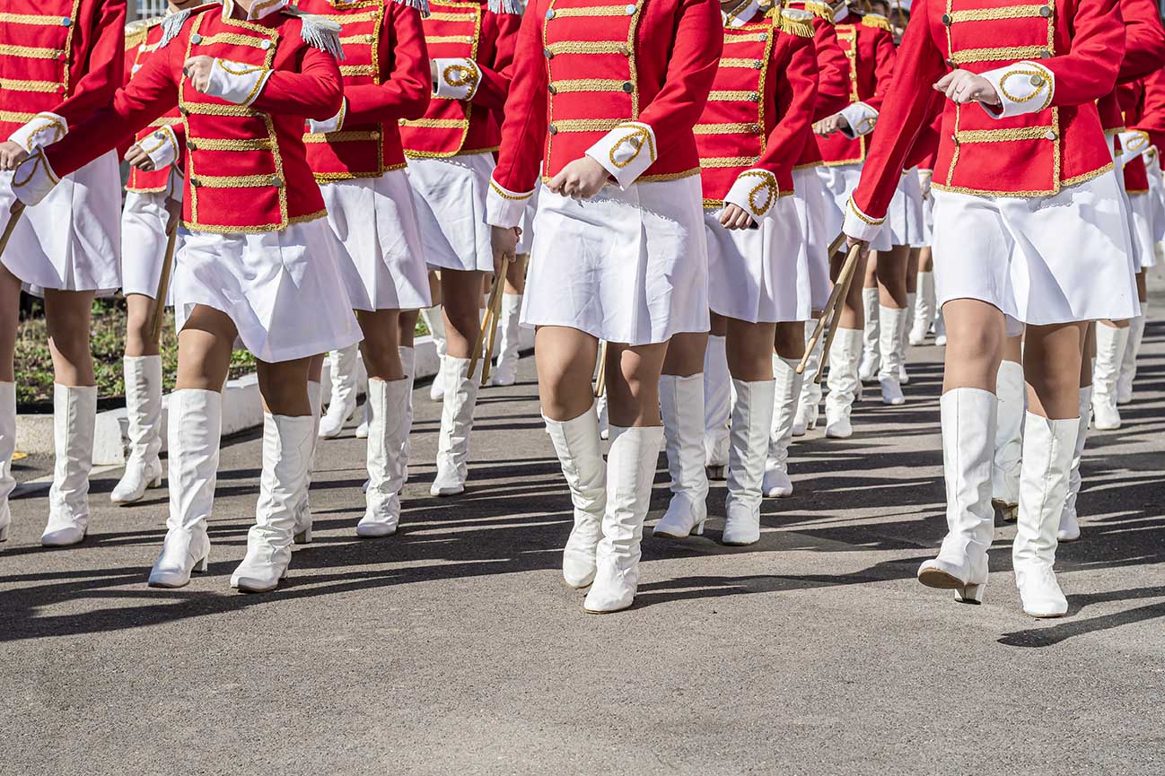 Parade marchers in white boots and red jackets. 