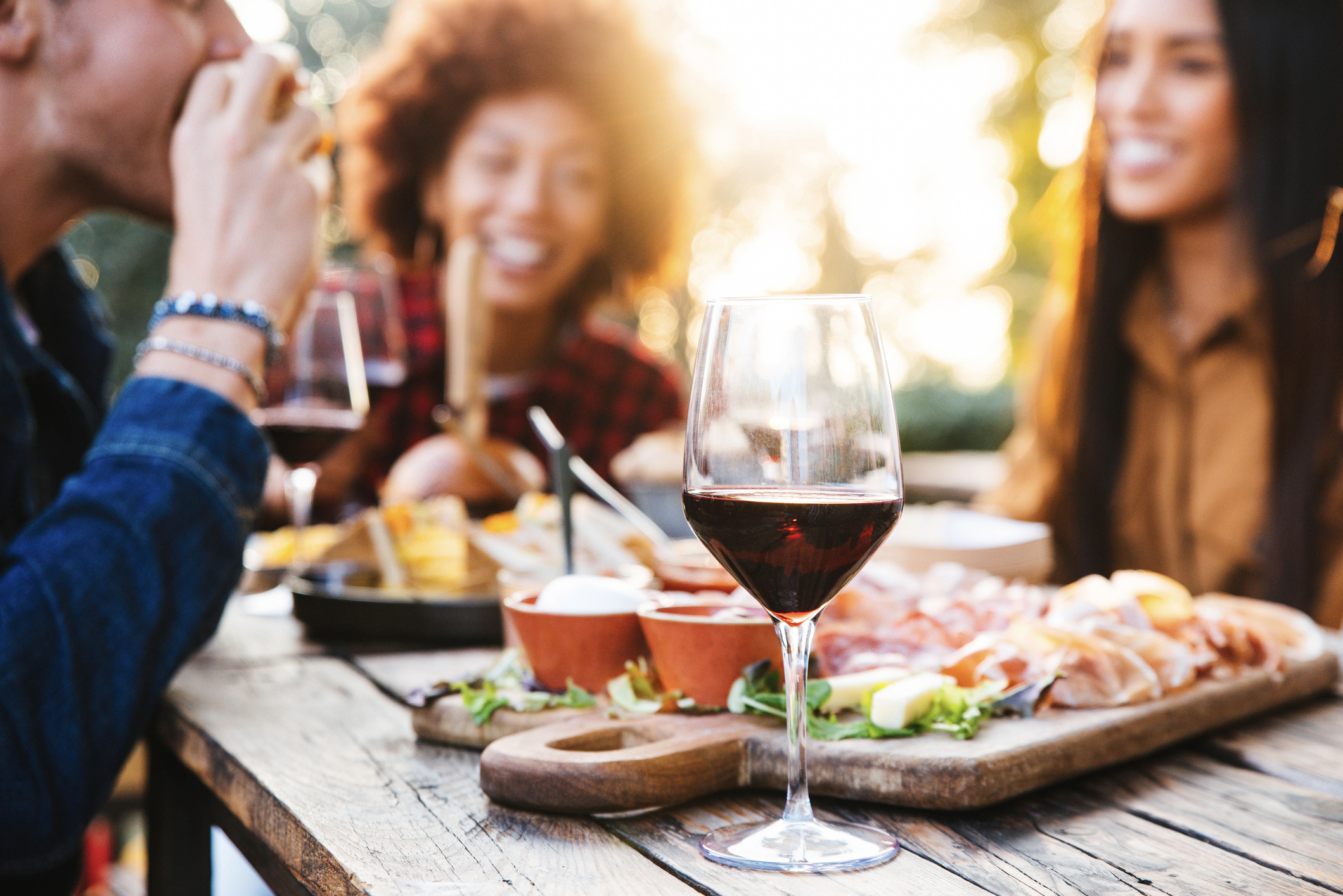 Diners enjoy wine and food on an outdoor tables.