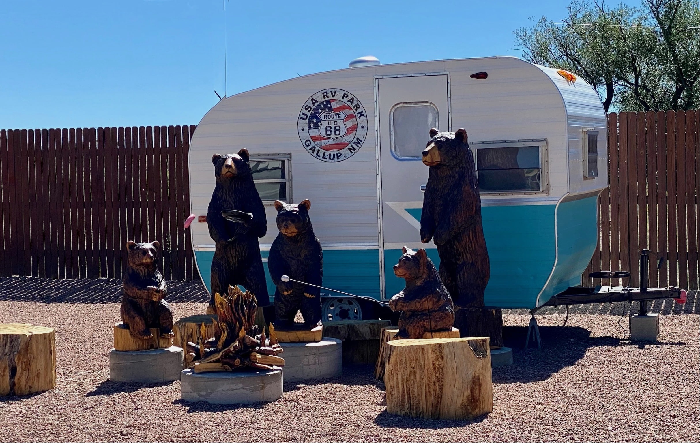 Statues of bears gathered around a travel trailer.