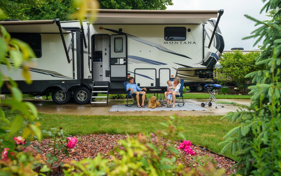 A couple lounging outside of their fifth-wheel