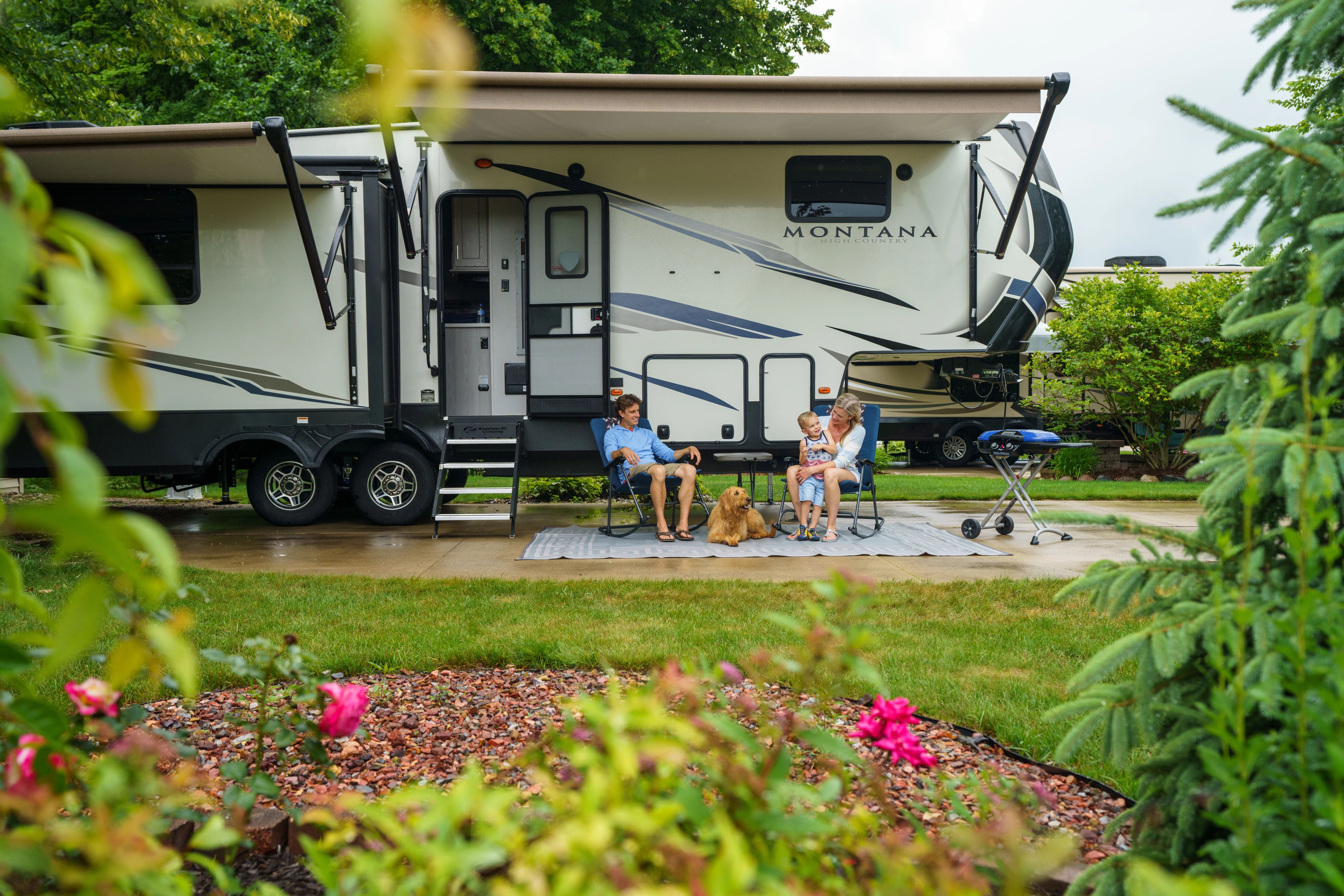 A couple lounging outside of their fifth-wheel