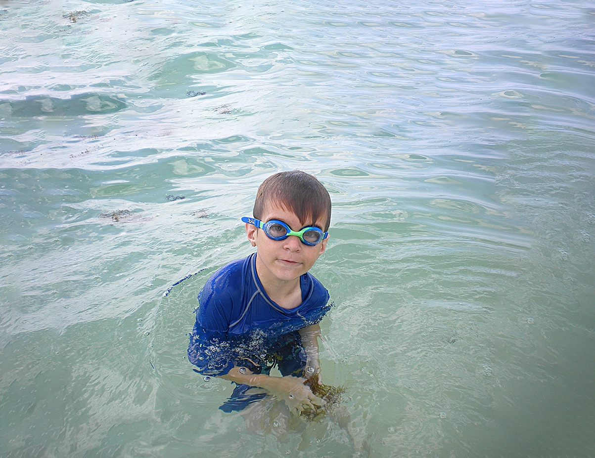 Garoto brincando na água da praia.