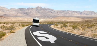 Motorhome driving on highway with dollar sign on blacktop