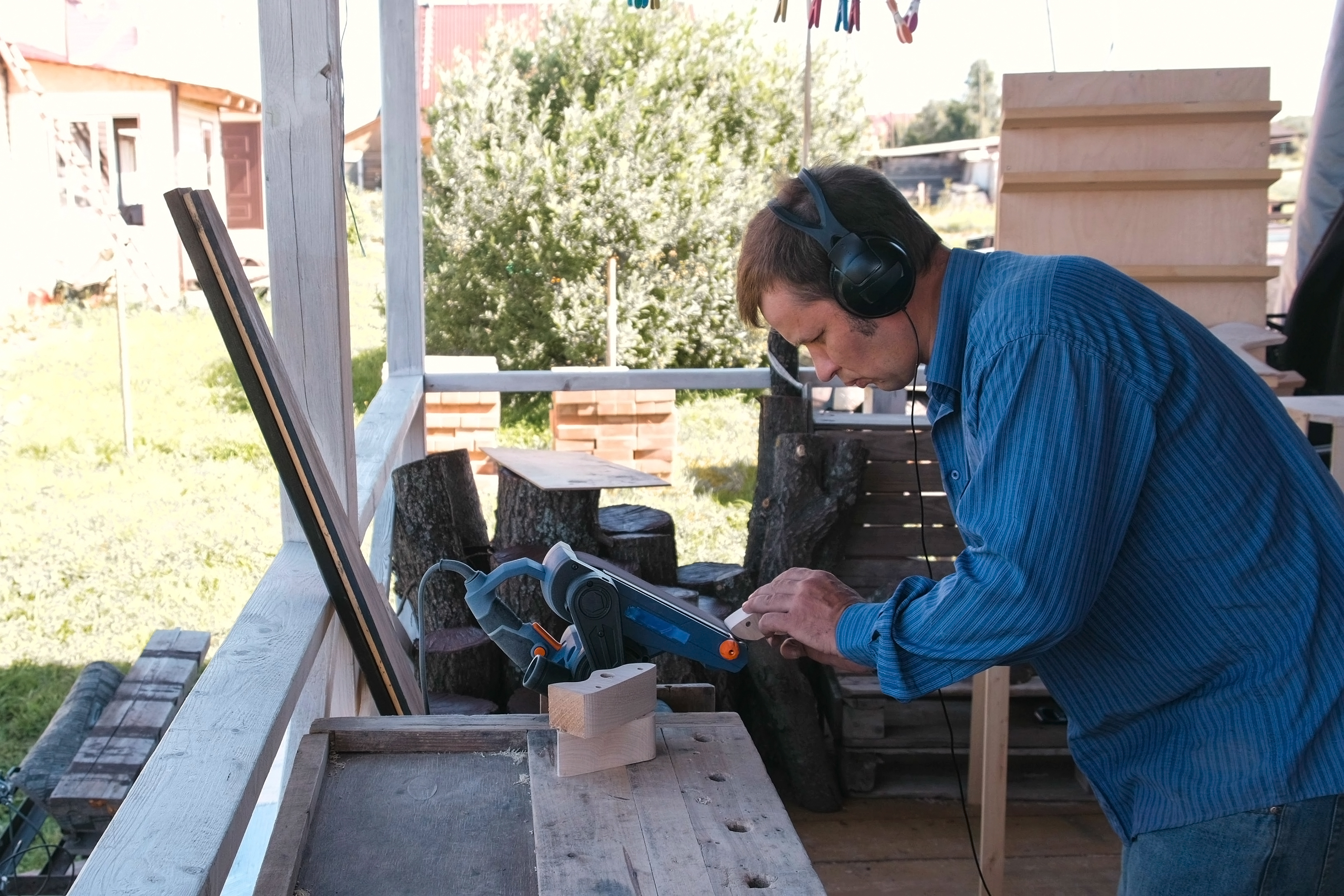 Carpenter polishes a wooden parts on a grinding machine